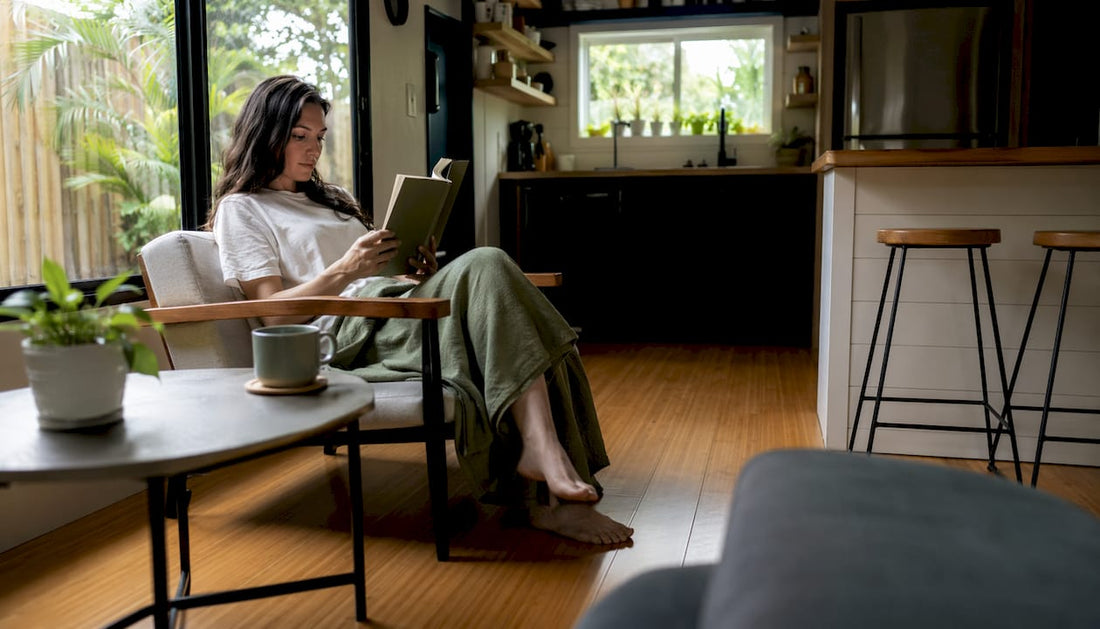 Woman reading inside tiny home living room with natural light