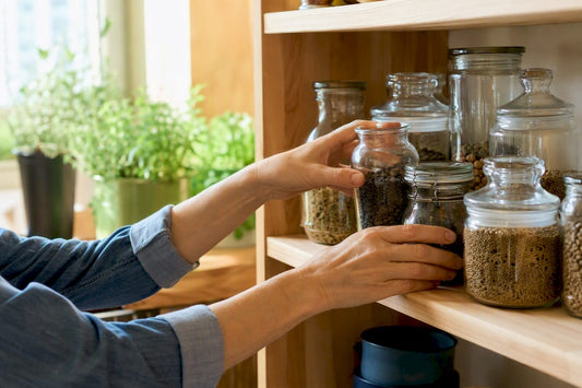 Hands placing seed jars on pantry shelf